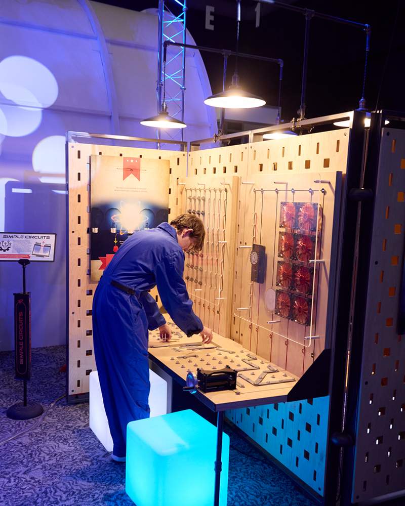 An employee at a space center stands over a table sorting materials.